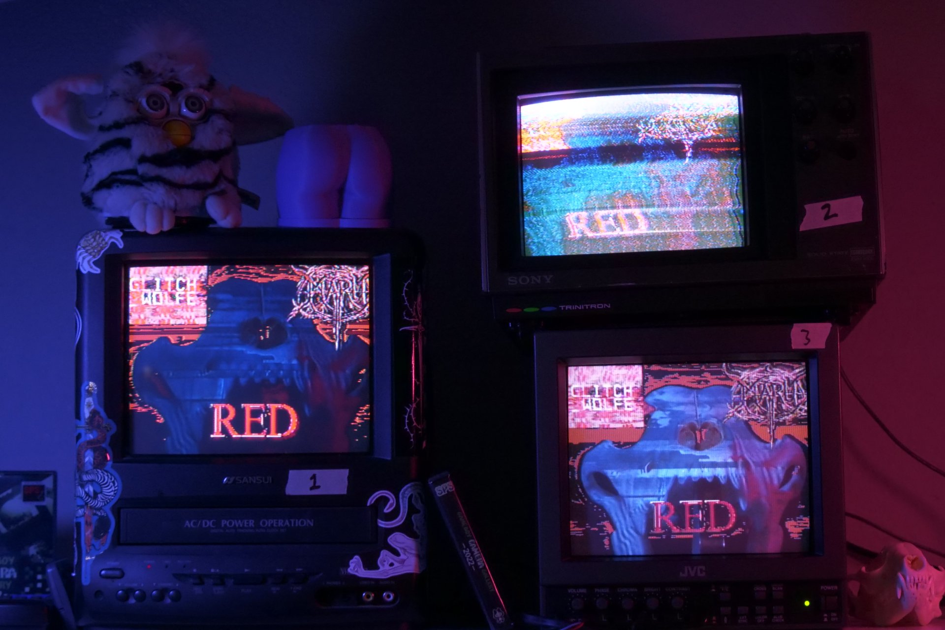 3 glitchy CRTs with the logo for RED displayed on them alongside a wolf skull